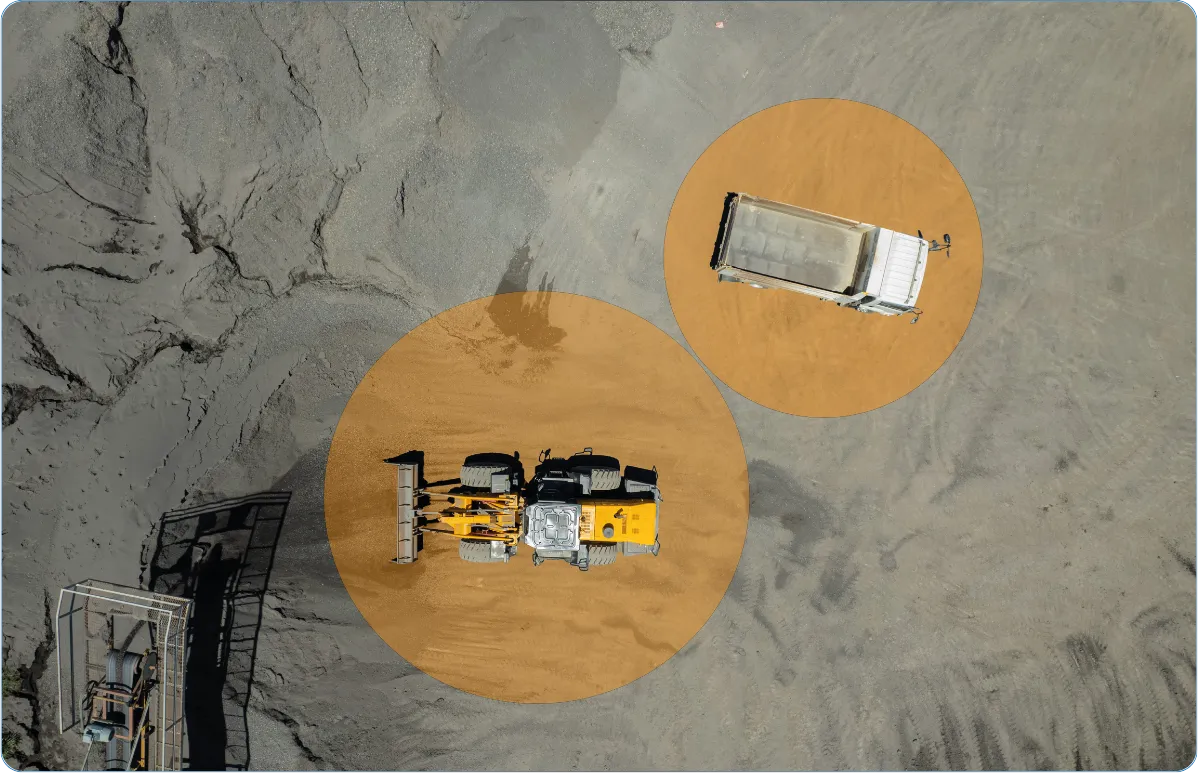 Vista aérea de uma operação de mineração com carregadeira e caminhão basculante destacados em áreas de monitoramento.