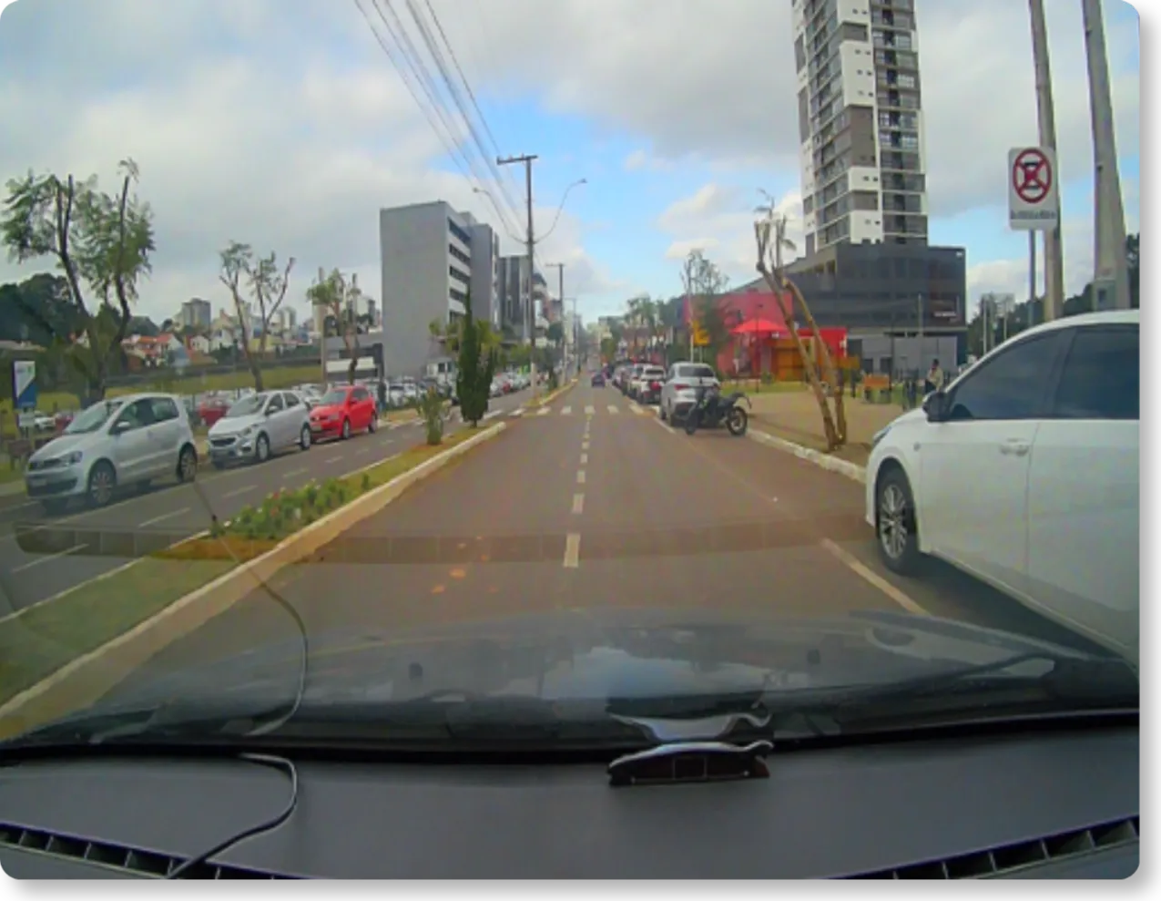 Imagem da câmera frontal em via urbana, com trânsito e veículos ao redor.